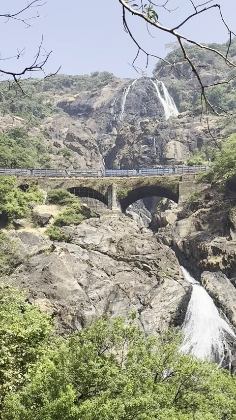 Vertical view of train crossing bridge over Dudhsagar Waterfalls Goa India 스톡 동영상 343156026