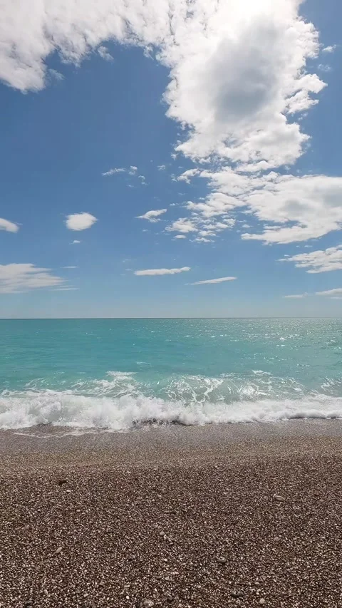 Vertical View of Turquoise Ocean Waves Crashing on Pebble Shore Stock Footage 339360219