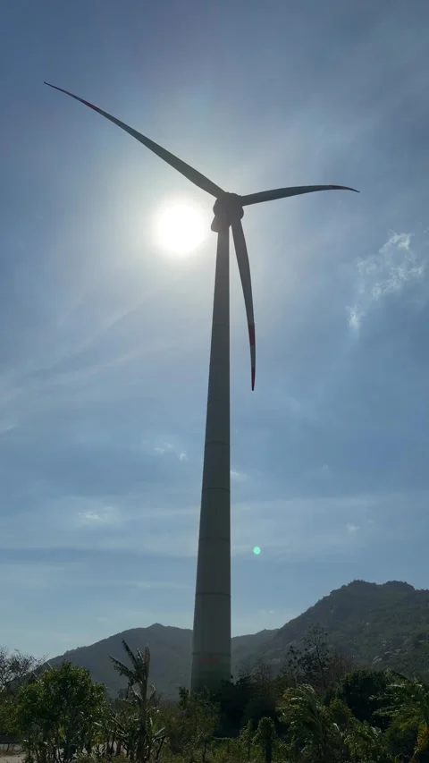 Vertical view of a wind turbine centered in frame, its blades rotating in front Stock Footage 329745696