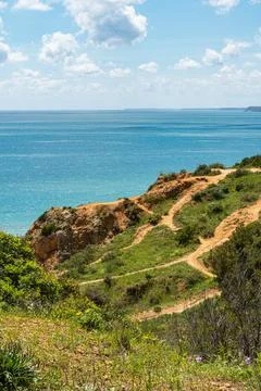 A vertical view of winding dirt paths traversing rugged green cliffs above .. Фото