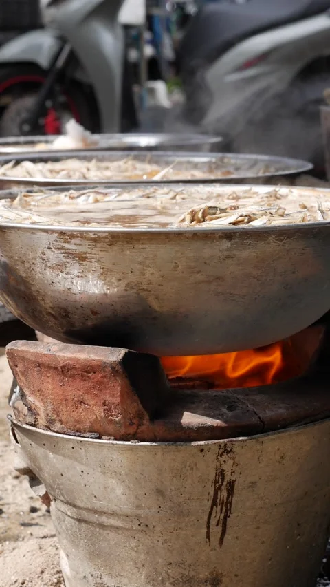 Vertical view of a wok with boiling liquid and anchovies simmering over fire 库存影片 332859593