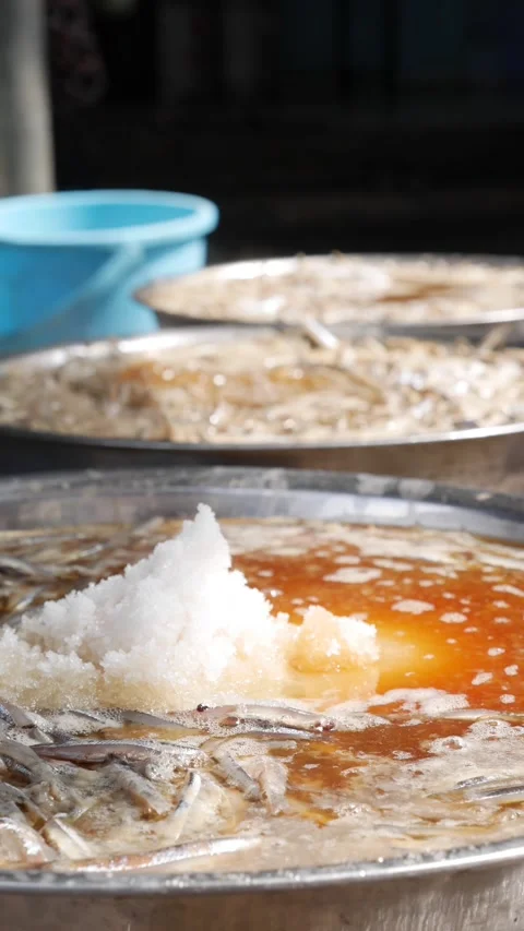 Vertical view of a wok filled with boiling liquid and anchovies placed over fire Stockbeeldmateriaal 334518234