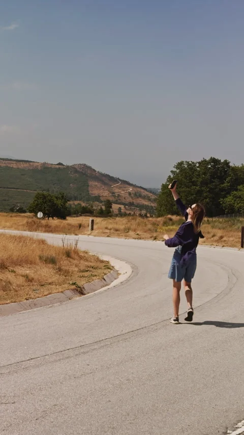 Vertical View of Woman Walking on Road Looking for Phone Signal Vídeos de archivo 346547662