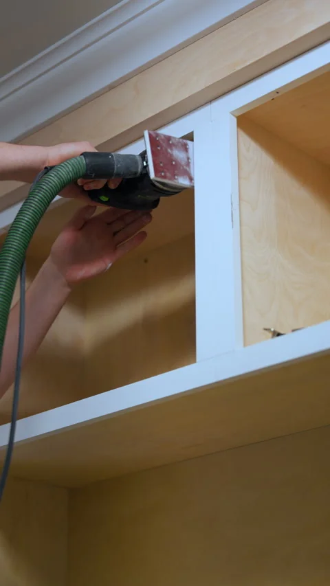 Vertical view of Worker sanding wooden cabinet surface with an electric orbital Видео 334024005