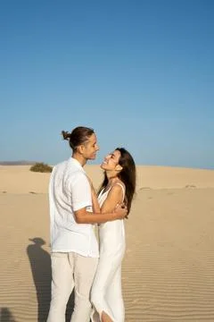 Vertical view of young couple looking to each other in sand dunes at the beach 写真素材