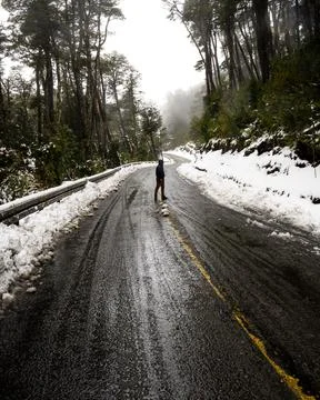 Vertical view of a young man surrounded by a snow-filled forest in the middle Stock Photos