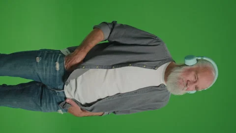 Vertical View.Green Screen. Modern Old Man Listens to Music in Headphones. Stock Footage 262224977