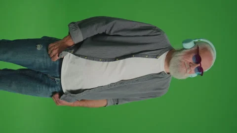 Vertical View.Green Screen. Modern Old Man Listens to Music in Headphones. Video stock 263400102