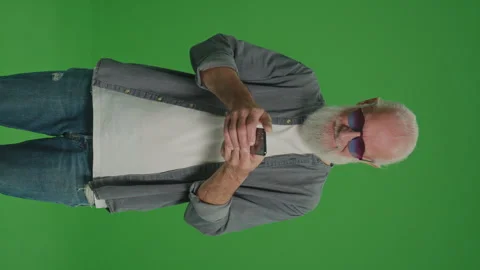 Vertical View.Green Screen.A Smiling Old Man Scrolls on the Phone. Stock Footage 249705951