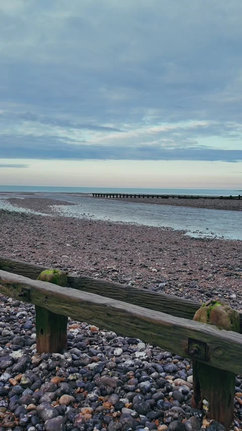 Vertical walking view on calm pebble beach with wooden groynes Stock Footage 309768652