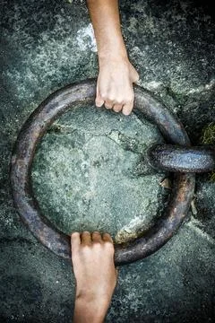 Vertical wallpaper of two hands pulling a giant iron ring pull from the ground f Stock Photos