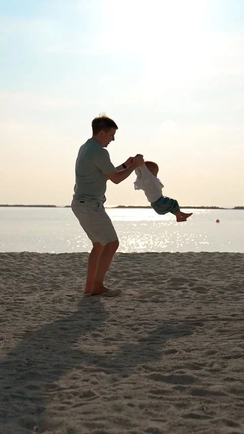 Vertical of The water father circles the child by the handles by the ocean coast Stock Footage 275641253