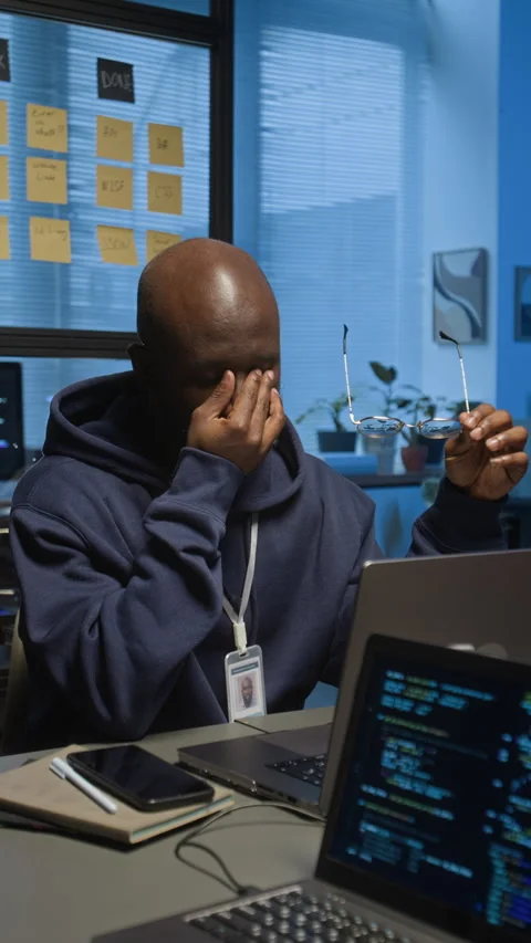 Vertical of Weary Black IT Manager in Hoodie Taking off Glasses to Rub His Eyes Stock Footage 329613831