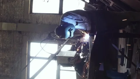 Vertical welder welds pipe. A welder in a protective helmet. Sparks fly out Stock Footage 246958193