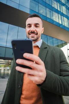 Vertical Well dressed guy using banking app with a cellphone. Young business man Stock Photos