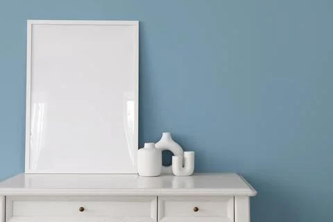 Vertical white picture frame mockup on a white dresser with modern vases agai Stock Photos