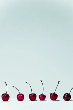 Vertical white summer background with red cherries at the bottom of the photo. Stock Photos