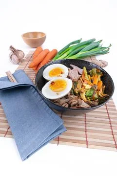 Vertical, wide studio shot of black bowl of ramen noodles with boiled eggs Stock Photos