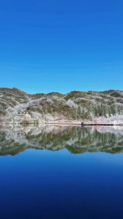 Vertical wide video of rippling deep blue lake water with snowy hills and bo Video stock 327583142