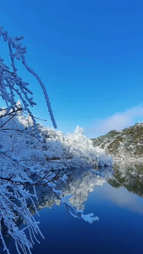Vertical wide video of rippling deep blue lake water with snowy hills and bo Video stock 327583401