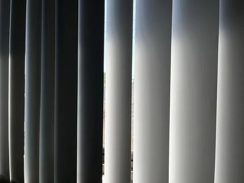 Vertical window blinds filtering soft sunlight Stock Photos