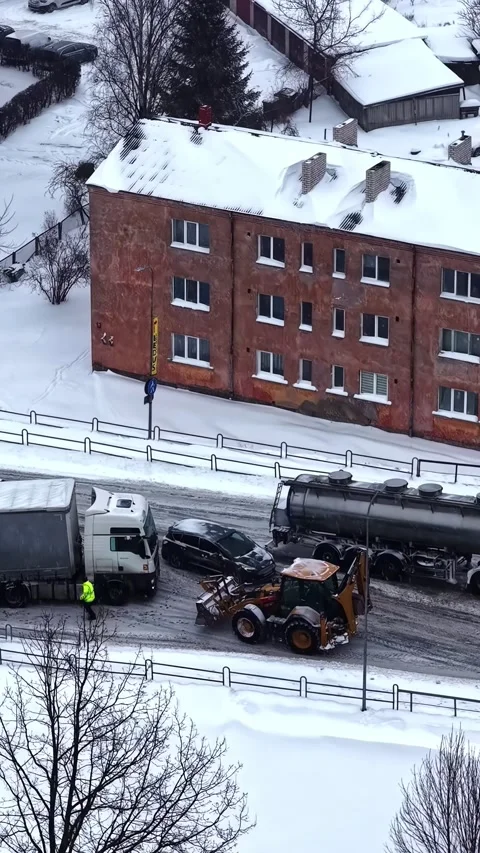 Vertical winter street view with trucks, snowplow loader and worker clearing a Stock Footage 336661275