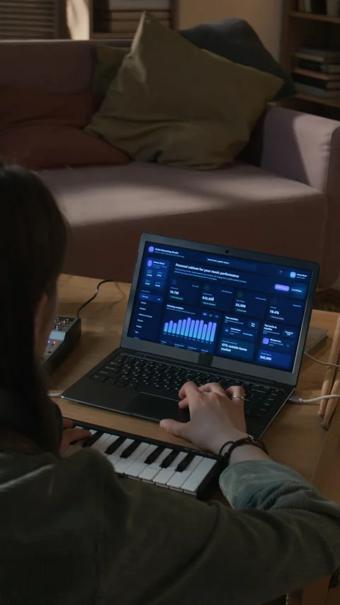 Vertical of Woman Checking Analytics on Online Music Platform on Laptop Indoors Stock Footage 335403242