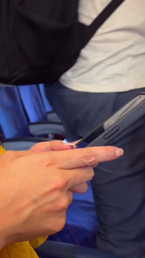 Vertical woman uses smartphone while seated in airplane. Modern travel setting Stock Footage 314466301