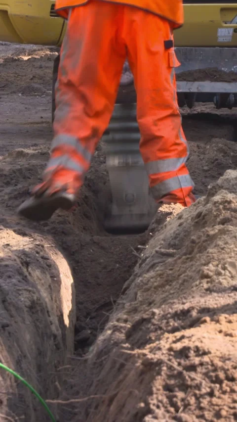 Vertical - workmen close cable slot using a tamping rammer machine Stock Footage 313279317