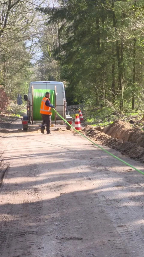 Vertical - workmen roll out underground fiber-optic cable laying Stock Footage 313279359