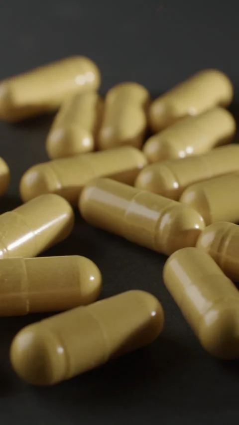 Vertical Yellow CoQ10 Capsules Macro Tracking Shot Video stock 332369890