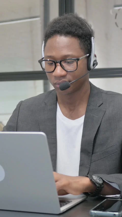 Vertical, Young African Man with Headset Working on Laptop 動画素材 325559888