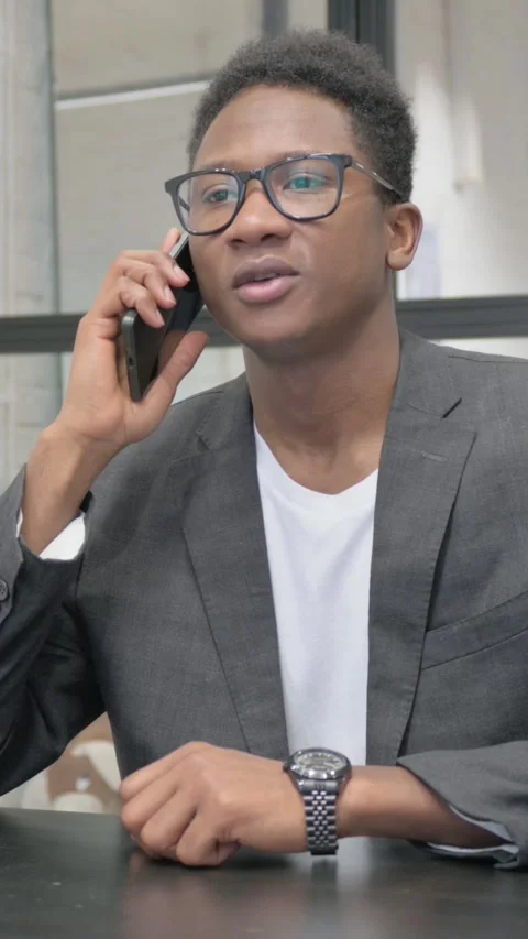 Vertical, Young African Man Talking on phone in Office Video stock 325560363