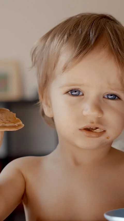 Vertical of Young Boy Holding a Spoon and a Cookie Stock Footage 274144754