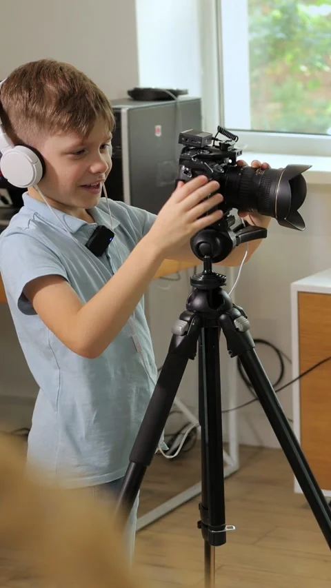 Vertical. A young boy learns videography and photography using a camera Video stock 312442616