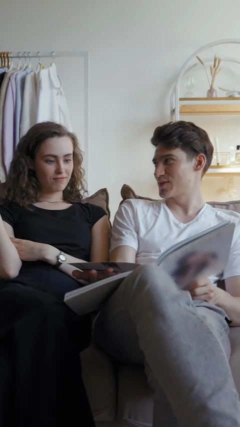 Vertical of Young couple sits on couch watching wedding album at home Stock Footage 276619713