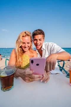 Vertical. Young couple using a smart phone to browse on internet sitting at a Stock Photos