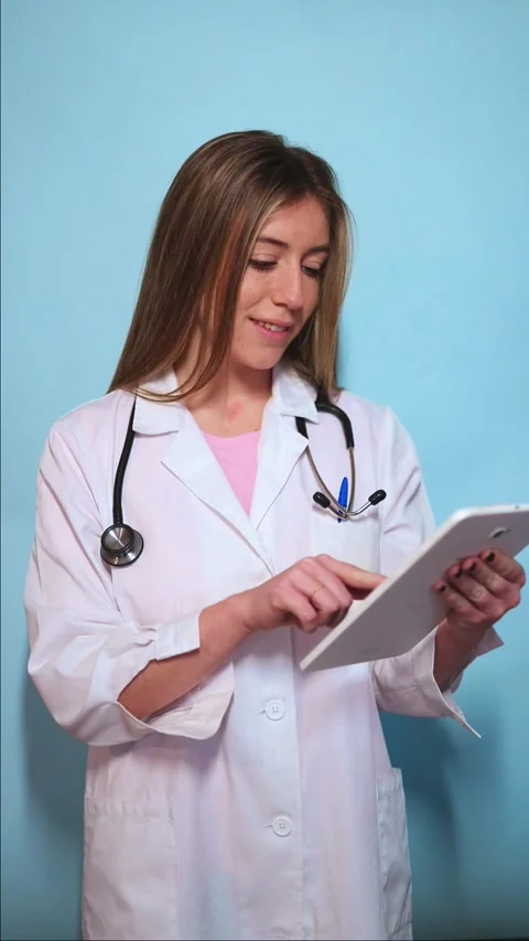 Vertical Young female doctor using a tablet on a blue background Stock Footage 297675315