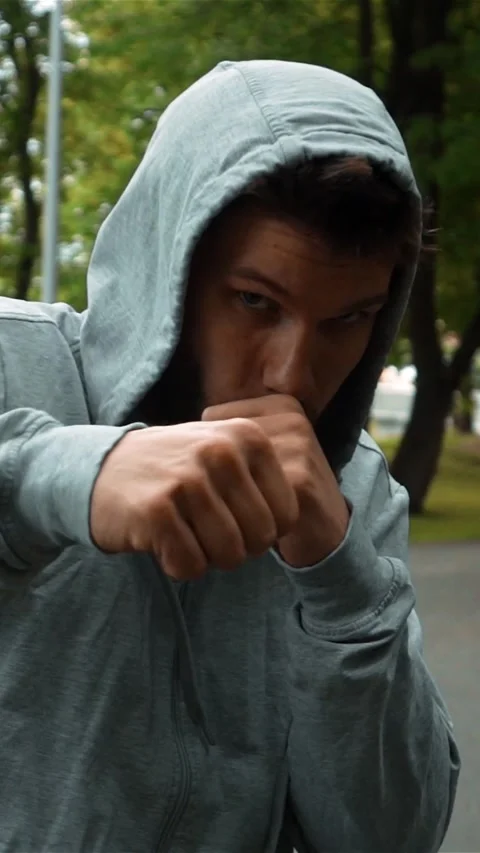 Vertical of Young fighter in gray hook running at park and brandish hands like Stock-Footage 278476243