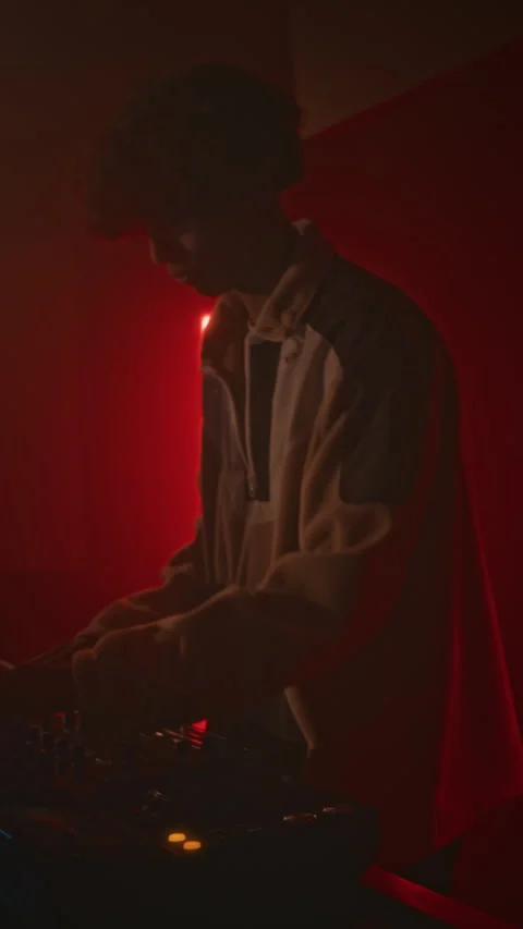 Vertical of Young Guy DJing with Controller in Red Neon Lit Club at Night Stock Footage 279963359