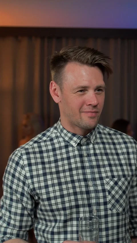 Vertical of Young handsome guy talking with his friend at private party Stock Footage 278483516