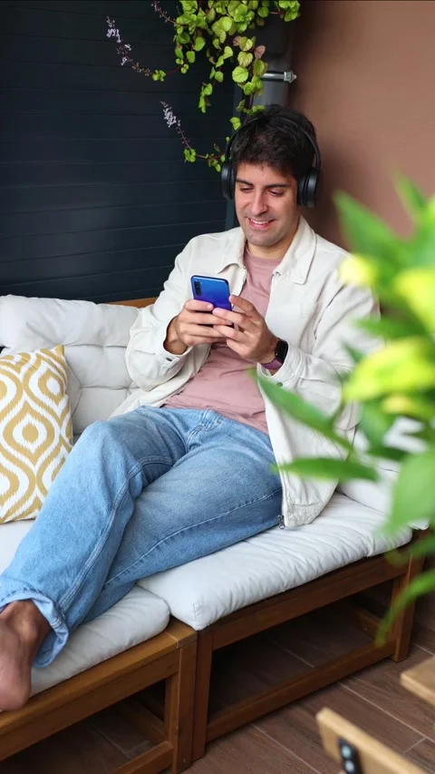 Vertical Young Hispanic man listening to music on his smartphone Stock Footage 319027710