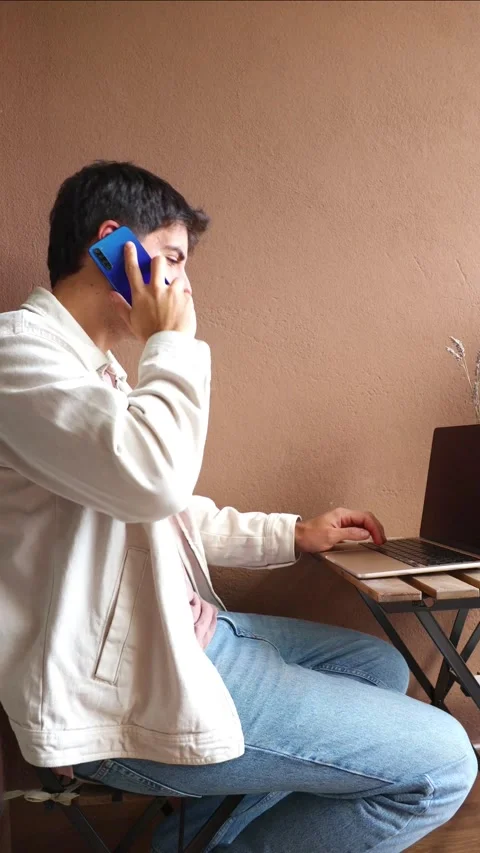 Vertical Young Hispanic man multitasking while teleworking from home Stock Footage 319027712