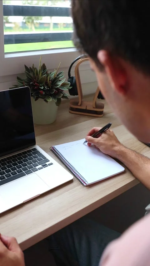 Vertical Young hispanic man teleworking from home writing in a notebook Stock Footage 319027704