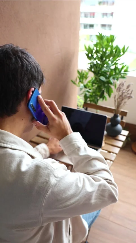 Vertical Young hispanic man teleworking and talking on smartphone Stock Footage 319027711