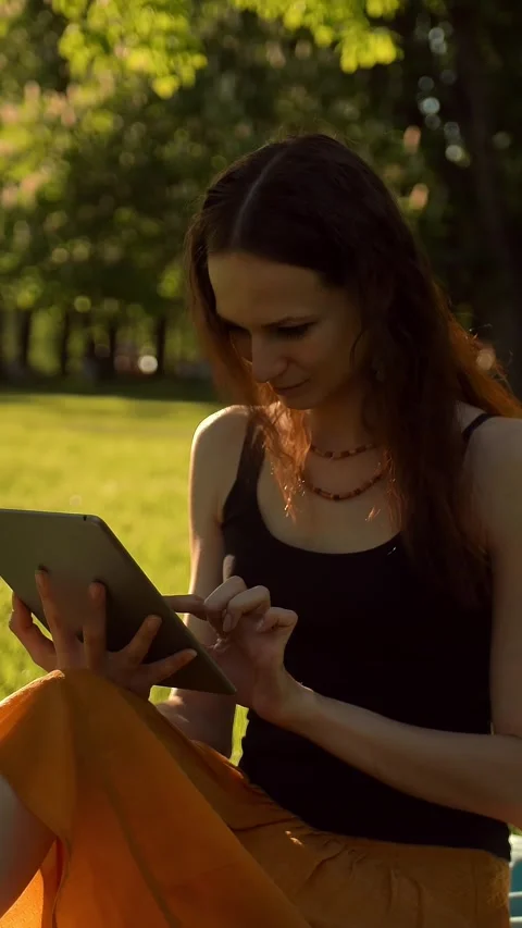 Vertical of Young lady browsing her tablet in the park. Stock Footage 278487585