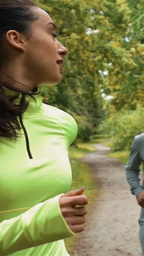 Vertical of Young lady runner looks back to his partner while running and Stock Footage 278479820