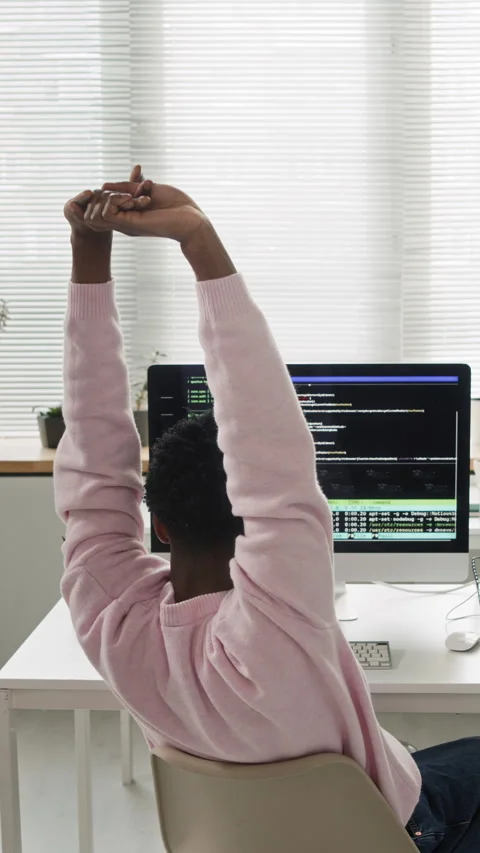 Vertical of Young Male Coder Stretching Arms while Working on Computer in Office Stock Footage 330132880