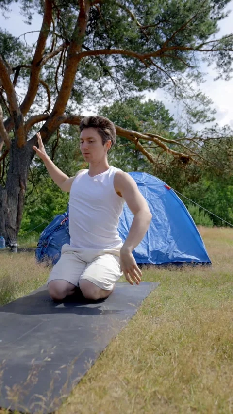 Vertical of Young man does yoga on mat uniting with forest nature Stock Footage 276385242