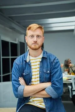 Vertical young red-haired programmer or businessman in modern office looking Stock Photos